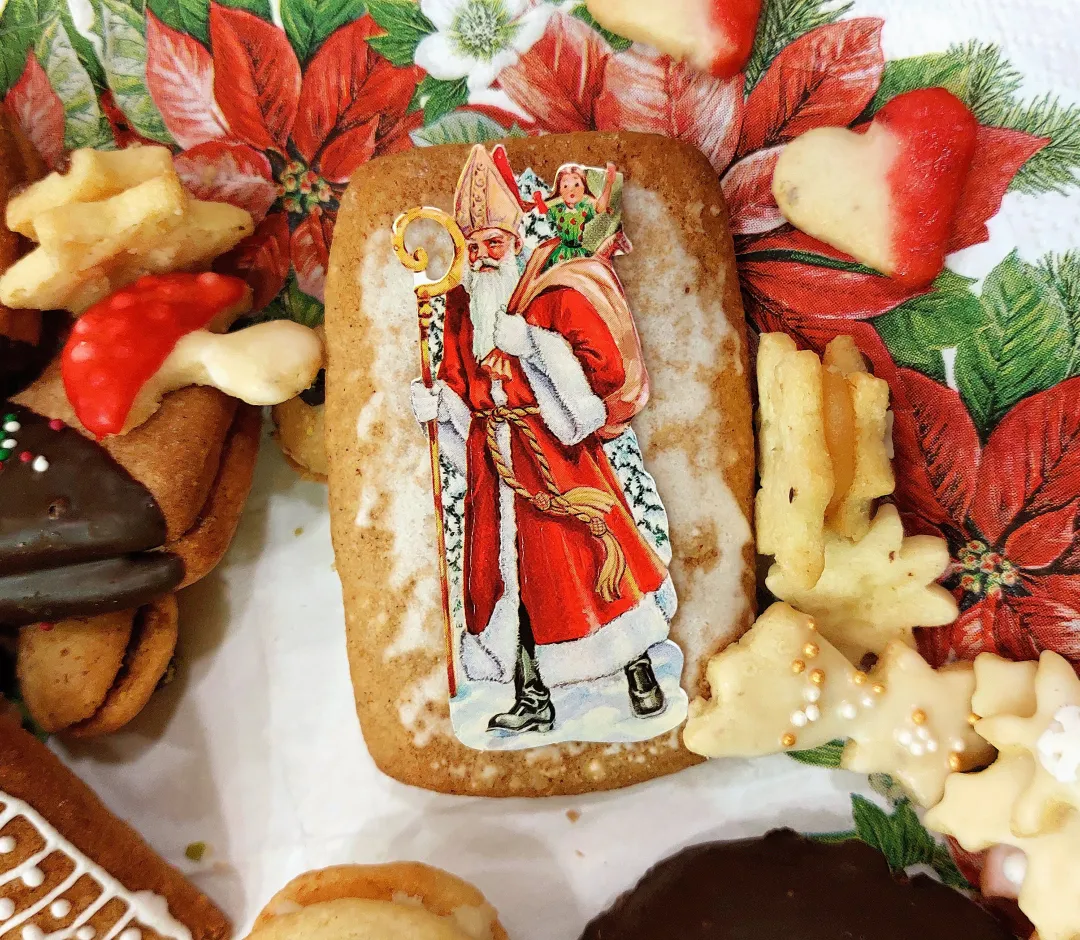 Bunter adventlicher Plätzchenteller, in dessen Zentrum ein Lebkuchen mit einer traditionellen Nikolaus-Oblate liegt.