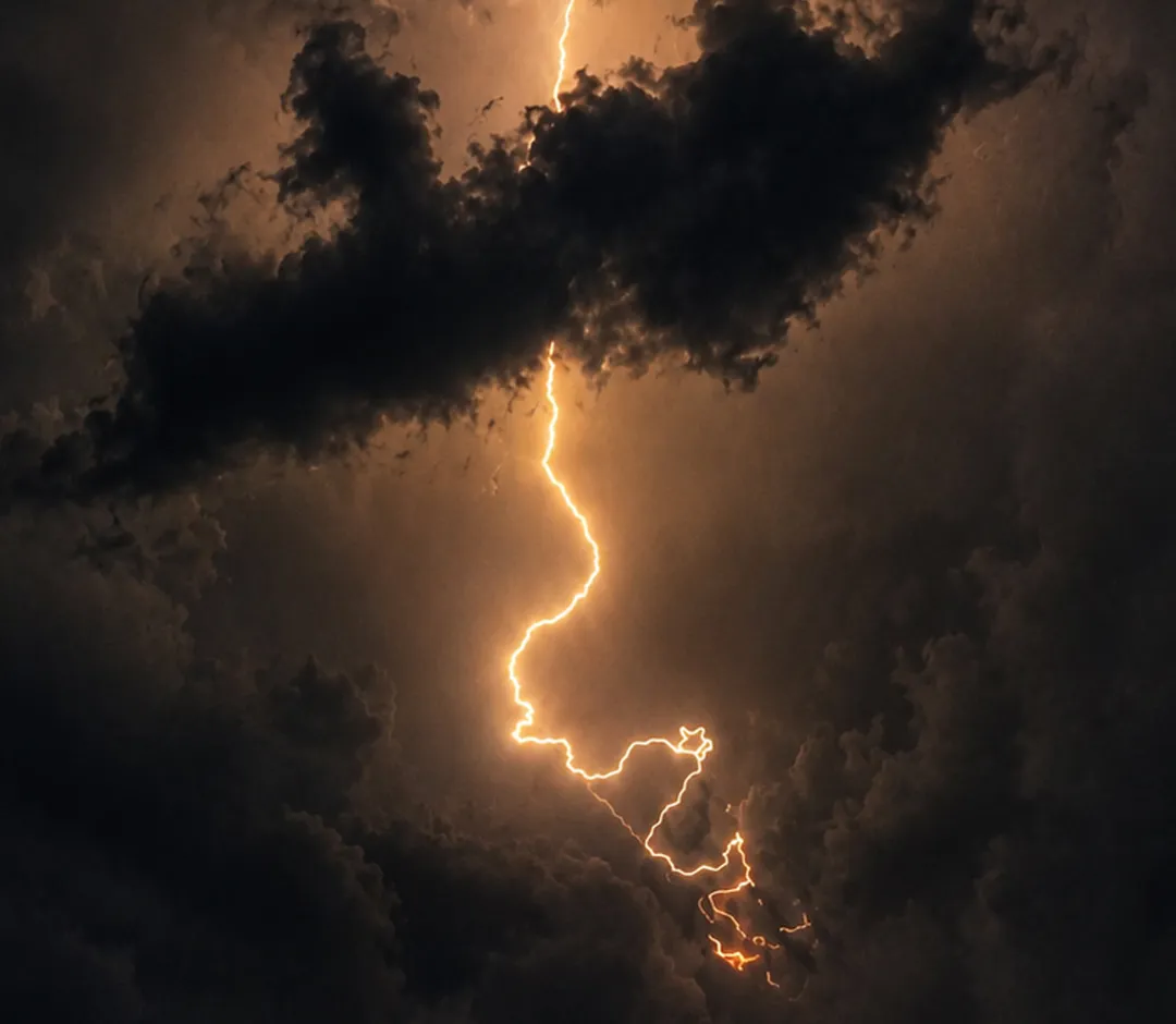Ein hell leuchtender Blitz durchzuckt einen wolkenschwarzen Himmel