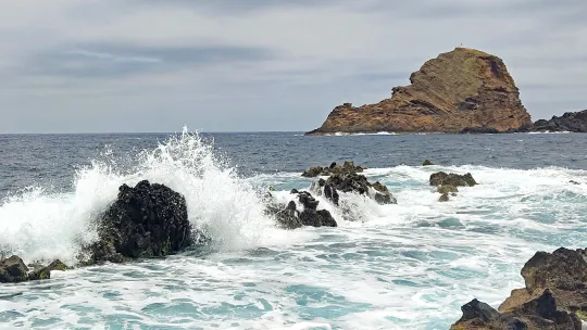 Felsen und eine Felsinsel an Küste im unruhigen Meer