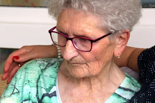 Eine alte Frau wird im Arm gehalten.