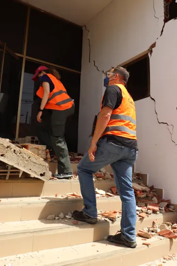 Zwei Mitarbeiter von Caritas International betreten ein von einem Erdbeben schwer beschädigtes Gebäude