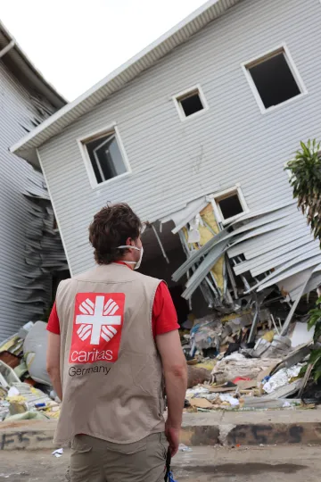 Jonas Brenner von Caritas international Deutschland steht in Venezuela vor einem vom Erdbeben zerstörten Haus