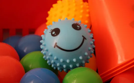 Farbige Gummibälle, auf einem ist ein lächelndes Gesicht aufgedruckt.