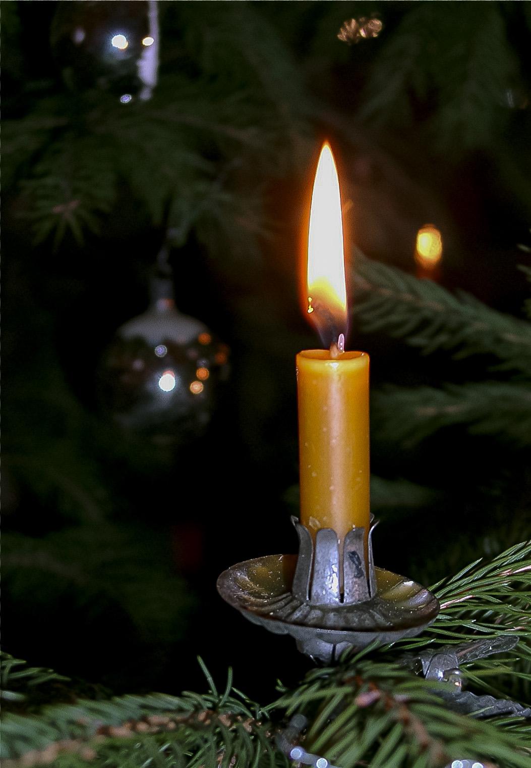 Brennende Kerze an einem Christbaum | Pfarrbriefservice.de